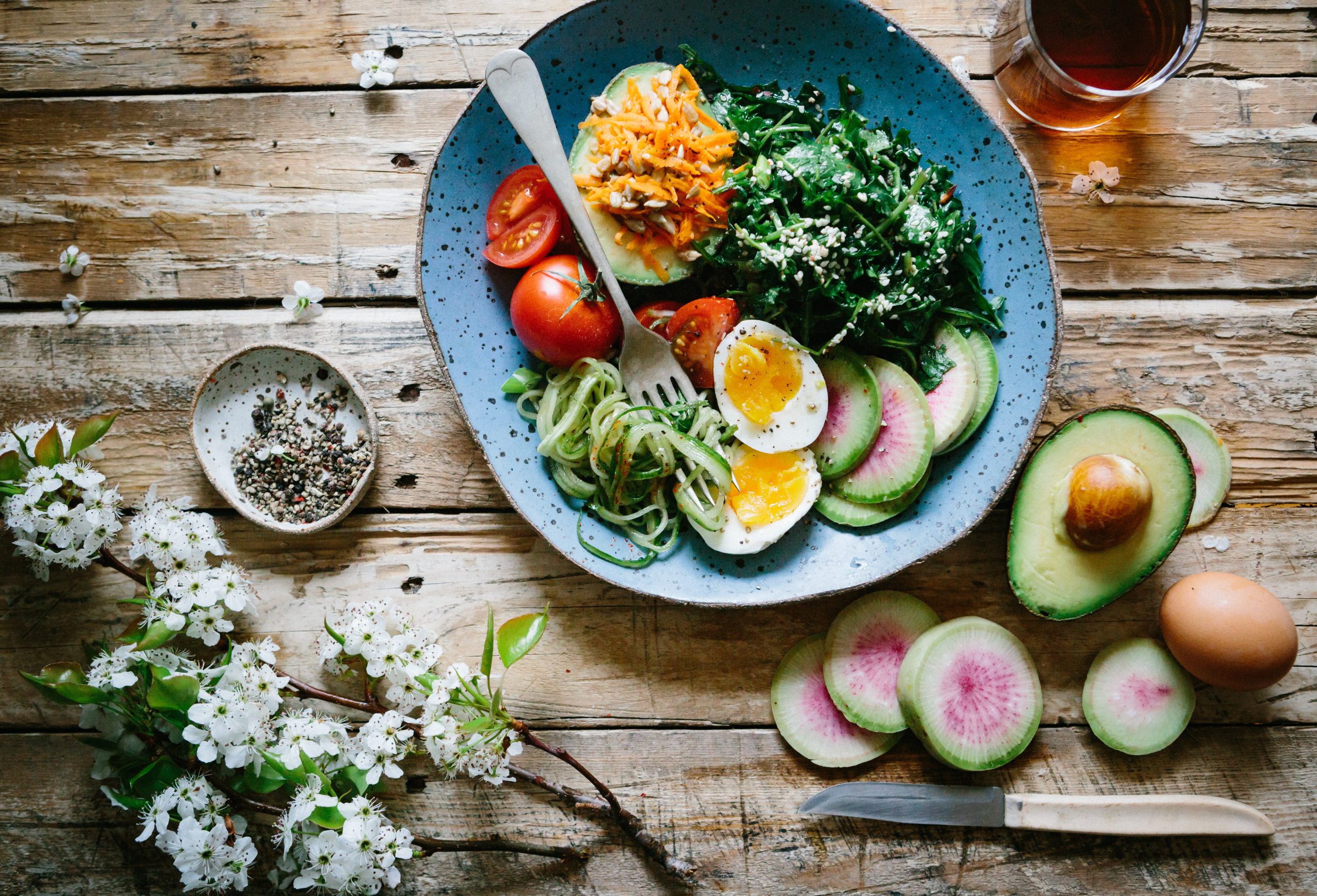Blue bowl on a wooden table filled with healthy colorful food