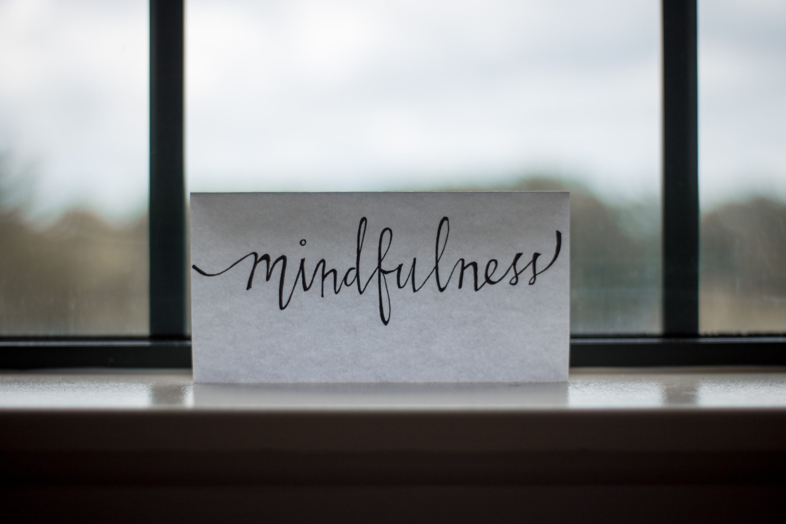 the word mindfulness written on a piece of paper in front of window